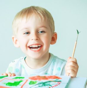 Happy boy with paint set after hearing test
