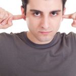 man trying to stop tinnitus by putting fingers in ears